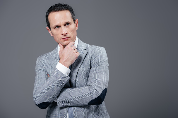 thoughtful adult businessman with hand on chin looking away isolated on grey - Photo, Image