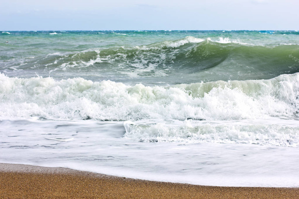 Mar tempestuoso e céu azul, espuma de mar branco em uma praia de areia amarela
. - Foto, Imagem