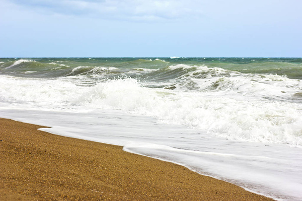 Stormachtige zee en blauwe lucht, Witte Zee schuim op een gele zandstrand. - Foto, afbeelding