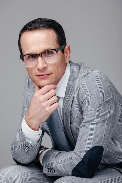 serious adult businessman with hand on chin looking at camera isolated on grey - Foto, imagen