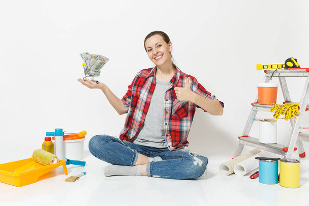 Woman holds bundle of cash money, supermarket grocery push cart for shopping. Instruments for renovation apartment isolated on white background. Wallpaper accessories for gluing. Repair home concept. - Photo, Image