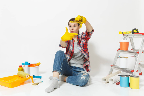 Spaß hübsche Frau in lässiger Kleidung sitzt auf dem Boden mit gelben Handschuhen, Instrumente für die Renovierung Wohnung isoliert auf weißem Hintergrund. Tapeten-Zubehör für Malwerkzeuge. Heimkonzept reparieren - Foto, Bild