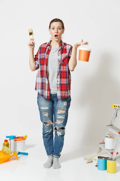 Full length portrait of fun cute woman with brush, paint can standing near instruments for renovation apartment home isolated on white background. Wallpaper, gluing accessories, tools. Repair concept. - Φωτογραφία, εικόνα