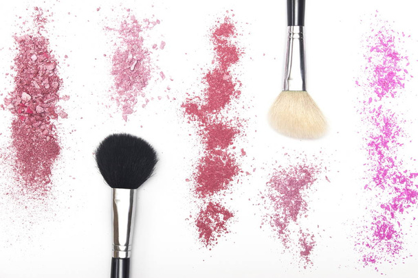 zerkleinerte Schattierungen von rosa Rouge und Kosmetikpinseln auf weißem Hintergrund - Foto, Bild