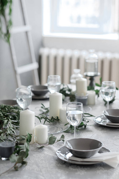 Table setting. Candles, plates and glasses - Foto, afbeelding