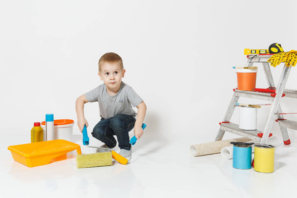 Aranyos kisfiú állandó felújítás apartman szoba elszigetelt fehér background-eszközökkel. Háttérkép, tartozékok ragasztás, festés eszközök. Fia otthon javítása. Szülői, gyermekkor fogalma. - Fotó, kép