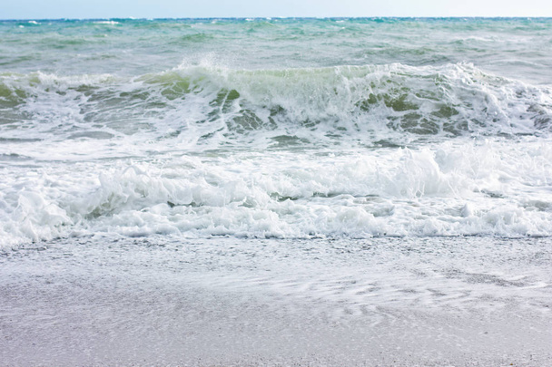 Mar tormentoso y cielo azul, espuma blanca en una playa de arena amarilla
. - Foto, imagen