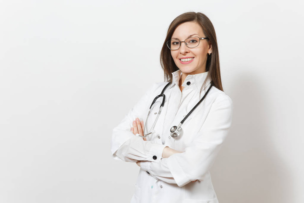 Smiling confident beautiful young doctor woman with stethoscope, glasses isolated on white background. Female doctor in medical gown holds hands folded. Healthcare personnel, health, medicine concept. - Fotó, kép