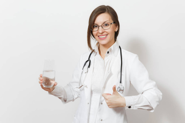 Χαμογελαστό γυναίκα γιατρός με το στηθοσκόπιο, γυαλιά που απομονώνονται σε λευκό φόντο. Γυναίκα γιατρό σε ιατρική φόρεμα κρατώντας το ποτήρι του νερού που δείχνει τους αντίχειρες επάνω. Νοσηλευτικού προσωπικού, την υγεία, την ιατρική έννοια. - Φωτογραφία, εικόνα