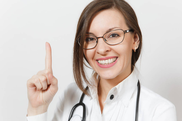 Крупним планом усміхнена лікарка зі стетоскопом, окуляри ізольовані на білому тлі. Жінка-лікар в медичній формі вказує вказівний палець вгору на копіювальний простір. Медичний персонал, концепція медицини
. - Фото, зображення
