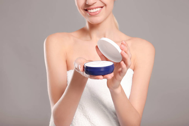 Young woman with jar of body cream on color background - Foto, afbeelding