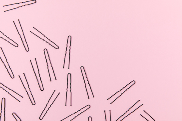 vista superior de grampos de cabelo pretos, isolados em rosa claro com espaço de cópia
 - Foto, Imagem