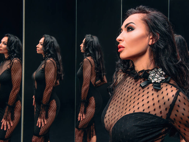 Portrait of beautiful brunette woman in black high heels shoes and dress standing near the mirrors - Fotografie, Obrázek