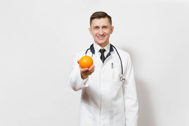 Усміхнений красивий молодий лікар ізольований на білому тлі. Чоловік-лікар в медичній формі, стетоскоп тримає апельсин. Медичний персонал, охорона здоров'я, концепція медицини. Правильне харчування. Копіювати простір
 - Фото, зображення