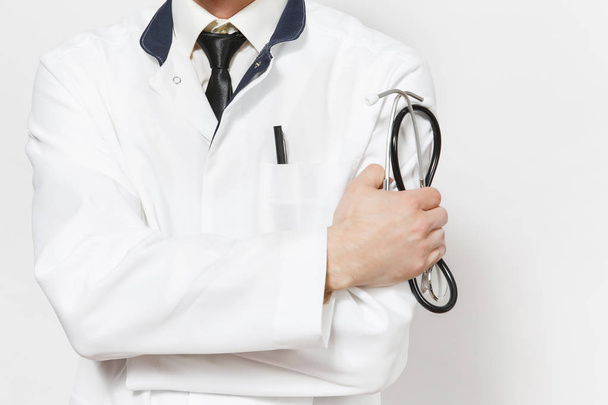 Close up cropped shot young doctor man isolated on white background. Male doctor in medical uniform holding stethoscope, holding hands folded. Healthcare personnel health medicine concept. Copy space. - Foto, Imagem