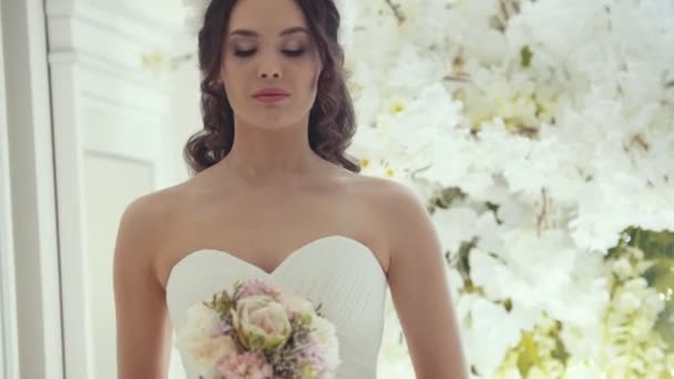 Krásná nevěsta ve svatebních šatech s květinami ve studiu - Záběry, video