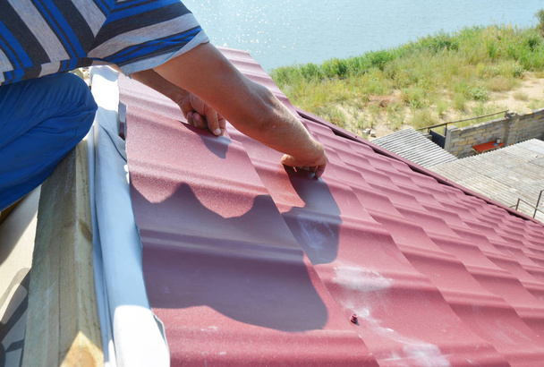 Budowa dachu. Dekarz, instalowanie dach metalowy arkuszy na dachu domu. - Zdjęcie, obraz