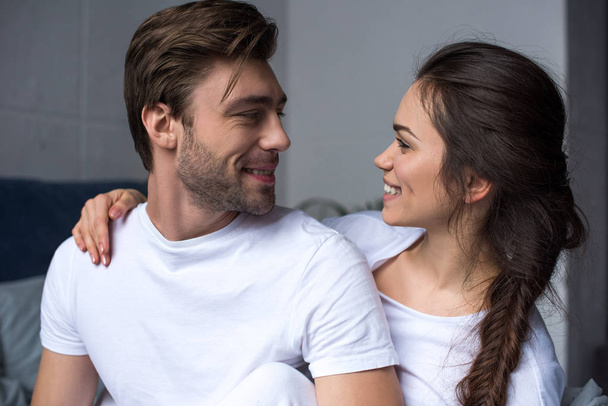 Young attractive couple hugging while sitting on bed - Photo, image