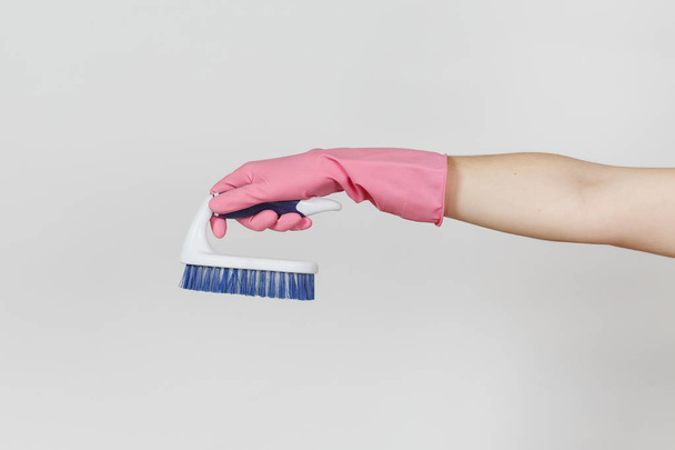 Close up van vrouwelijke hand in roze handschoenen horizontaal witte borstel met harde vezels houdt voor het reinigen met blauwe geïsoleerde op witte achtergrond. Schoonmaak leveringen concept. Ruimte voor advertentie kopiëren - Foto, afbeelding