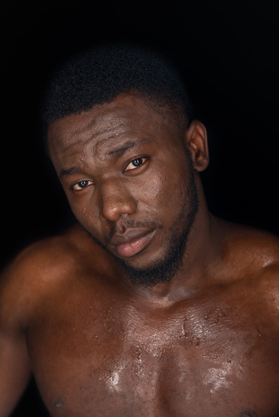 handsome sweaty young african american man looking at camera isolated on black - Photo, Image
