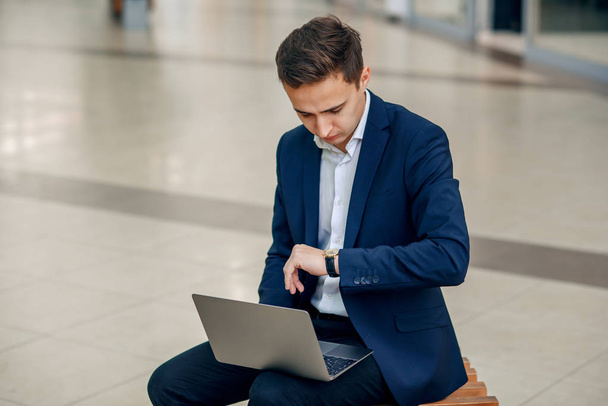 Successful young businesswoman working on a laptop sitting on a bench. Stylish handsome man in suit. Forex cryptocurrency trading, business concept. - 写真・画像