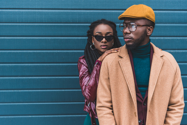 beautiful stylish young african american couple in jacket and overcoat posing together outside  - Фото, изображение