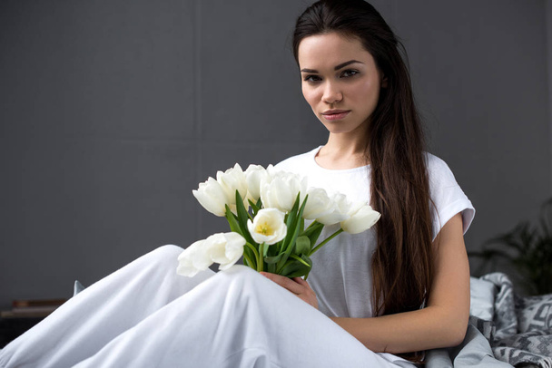 Beautiful young girl with white bouquet in bed - Fotografie, Obrázek
