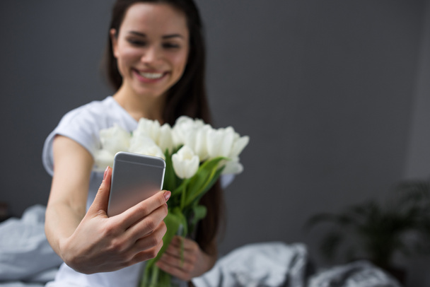 Brünettes Mädchen macht Selfie von sich mit weißen Tulpen - Foto, Bild