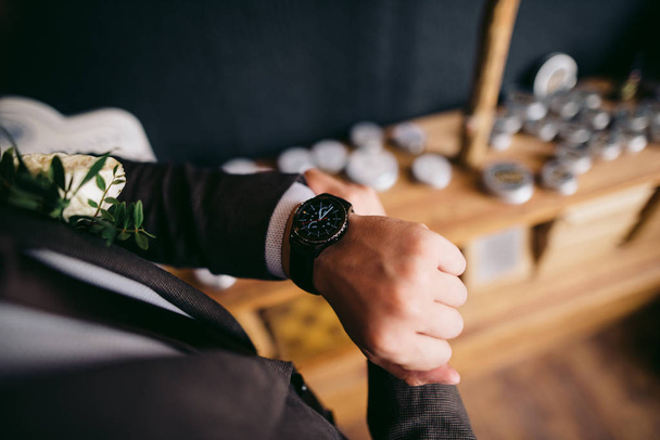 Groom in brown jacket puts watches - Photo, Image