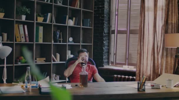Hombre de negocios sentado en la silla de la oficina con la cara pensativa y beber whisky
 - Imágenes, Vídeo
