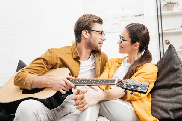 handsome young man with guitar flirting with girlfriend at home - Foto, Bild