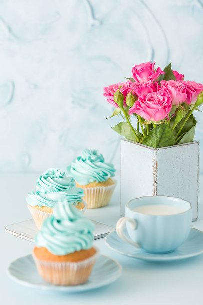 装飾カップケーキ、ミルクとコーヒーのカップとピンクのバラの花束とブルーのパステル垂直バナー. - 写真・画像