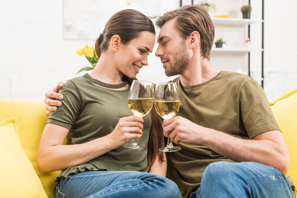 抱きしめるカップルで一緒にワインを飲んでソファの自宅 - 写真・画像