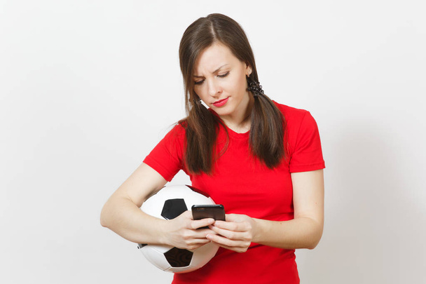 Европейская молодая сердитая кричащая женщина, футбольный фанат или игрок в жёлтой форме отправляют смс на мобильный телефон, держат футбольный мяч изолированным на белом фоне. Спорт, футбол, концепция здорового образа жизни
. - Фото, изображение
