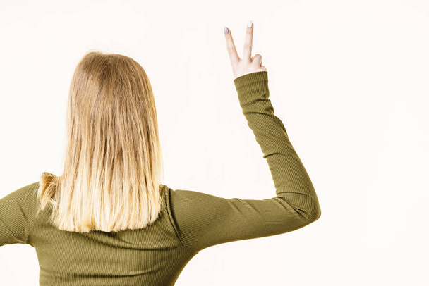 Back view of woman showing peace gesture - 写真・画像