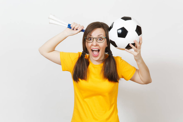 欧州女性の笑みを浮かべて、2 つ楽しいポニー尾、フットボールのファンや眼鏡、黄色の均一保持サッカー パイプ、白い背景で隔離のボールの選手。スポーツ、サッカー、健康、健康的なライフ スタイルのコンセプト. - 写真・画像