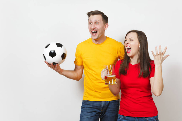 Spaß verrücktes junges Paar, Frau, Mann, Fußballfans in gelb-roter Uniform feuern ihre Mannschaft mit einem Bierkrug an, Fußball isoliert auf weißem Hintergrund. Sport, Familienfreizeit, Lifestylekonzept. - Foto, Bild