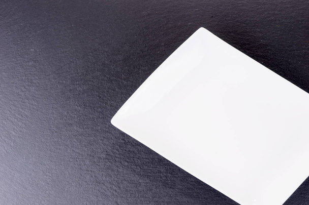 コピー スペースを持つ黒いスレート板上の空の白いセラミック ボウル - 写真・画像