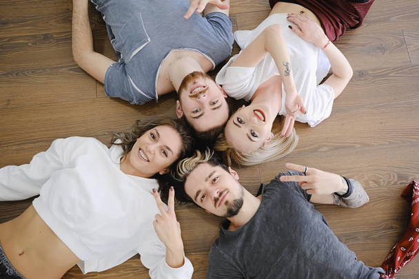 Vue de dessus quatre jeunes gens joyeux allongés sur le sol
 - Photo, image