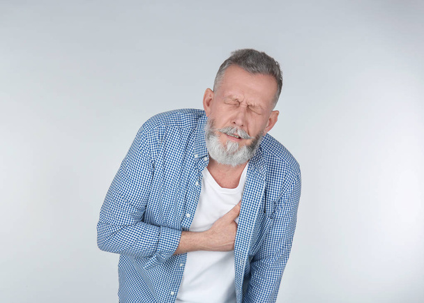 Ο άνθρωπος που υποφέρει από πόνο στο στήθος σε ανοιχτόχρωμο φόντο - Φωτογραφία, εικόνα