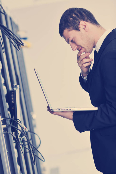 young engeneer business man with thin modern aluminium laptop in network server room - 写真・画像