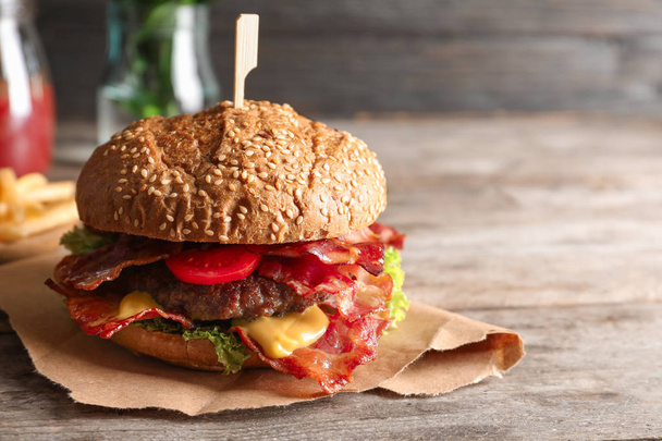 Tasty burger with bacon on wooden table - Foto, immagini