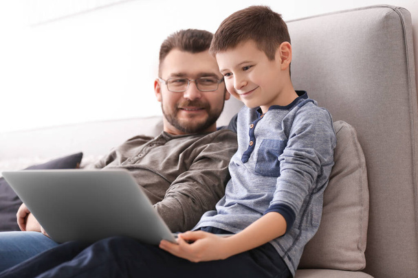 Little boy and his dad using laptop at home - 写真・画像