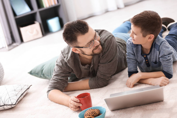 Little boy and his dad using laptop at home - Foto, Bild