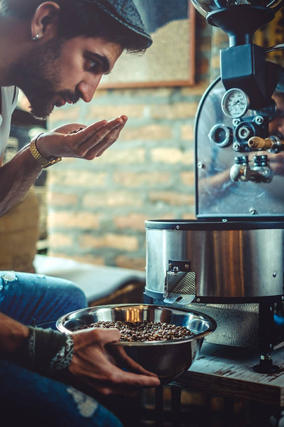 Homem cheirando grãos de café que ele assou
 - Foto, Imagem