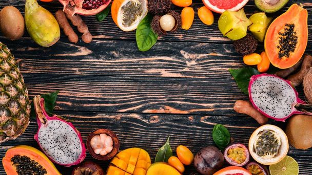 Tropical fruits, papaya, Dragon Fruit, rambutan, tamarind, cactus fruit, avocado, granadilla, carambola, kumquat, mango, mangosteen, passionfruit, coconut. On a wooden background. - Fotó, kép