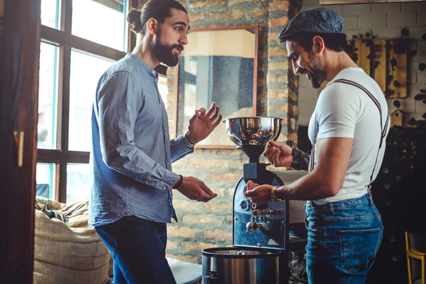 Proprietari maschi guardando chicco di caffè dal torrefattore caffè
 - Foto, immagini