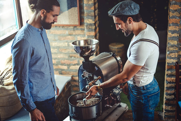 Мужчины владельцы смотрят на кофе жаровня машина
 - Фото, изображение