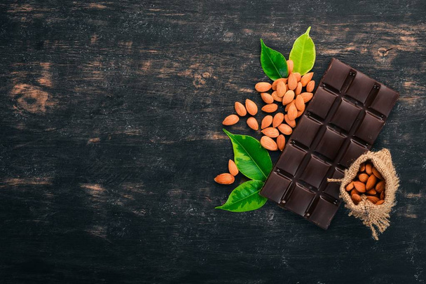 Dark chocolate with almond nuts. On a wooden background. Top view. Copy space for text. - Photo, Image