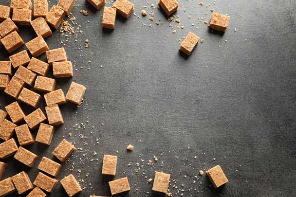 Cubes of brown sugar on gray background - Foto, afbeelding